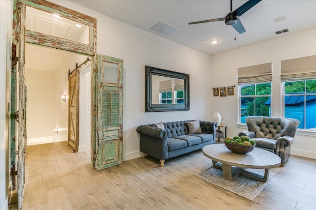 living room featuring light wood-type flooring, baseboards, visible vents, and ceiling fan
