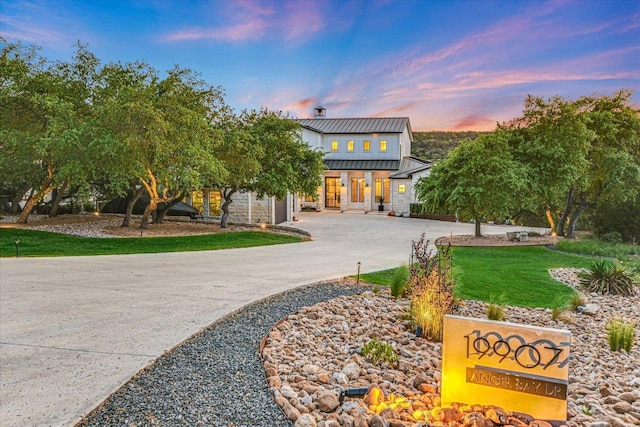 view of front of house with stone siding and curved driveway