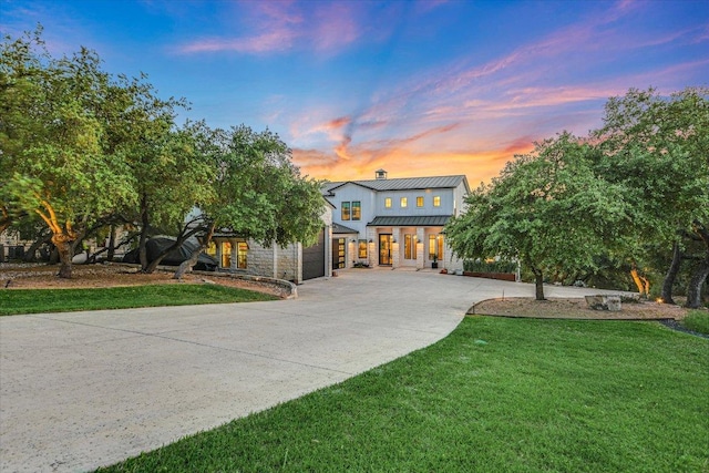 view of front of house featuring a lawn, a standing seam roof, driveway, and metal roof