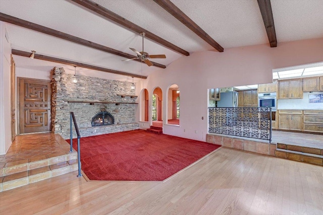 9401 Cedar Crest Dr, Austin, TX 78750 - unfurnished living room featuring a stone fireplace, wood finished floors, beamed ceiling, and a ceiling fan