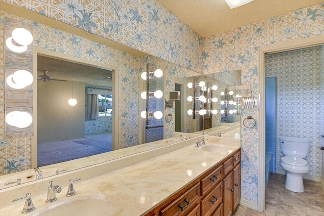 9401 Cedar Crest Dr, Austin, TX 78750 - bathroom featuring double vanity, wallpapered walls, toilet, and a textured ceiling