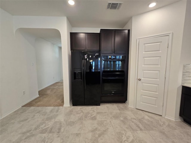 kitchen featuring dark brown cabinets, black appliances, arched walkways, baseboards, and visible vents
