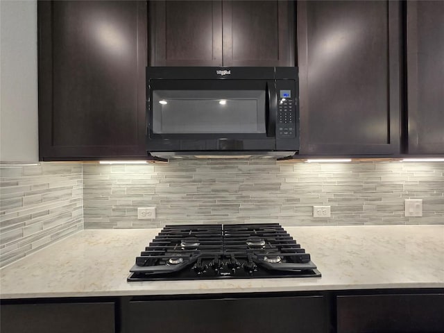 kitchen featuring dark brown cabinets, decorative backsplash, light stone counters, and black appliances