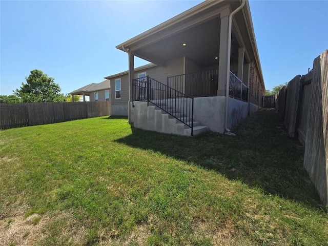 exterior space featuring stairway, a fenced backyard, and a yard