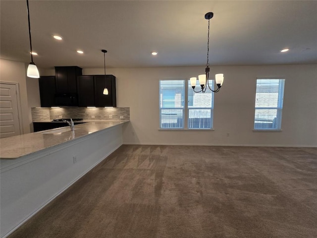 kitchen with tasteful backsplash, carpet floors, an inviting chandelier, baseboards, and dark cabinets