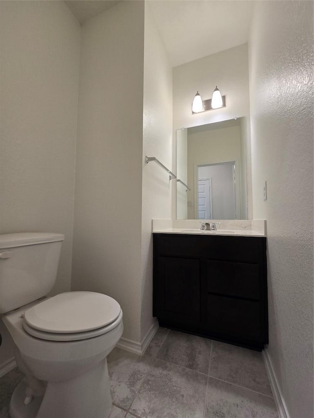bathroom featuring toilet, vanity, and baseboards