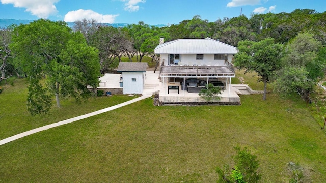 back of house featuring a yard, an outbuilding, a deck, and a patio