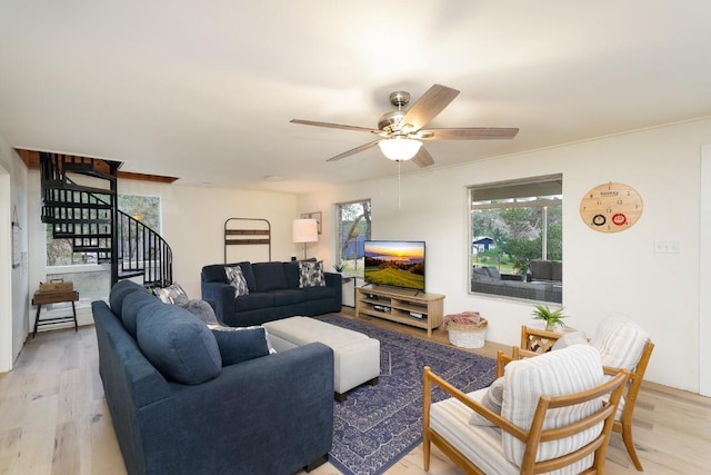 living room with light wood-type flooring, a ceiling fan, and stairs