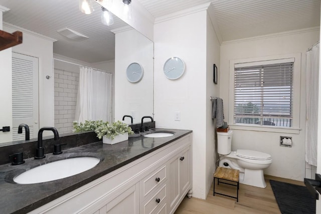 bathroom featuring toilet, crown molding, wood finished floors, and a sink