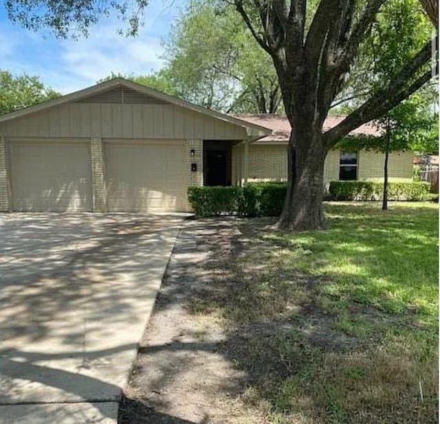 ranch-style home featuring a garage, driveway, and a front lawn