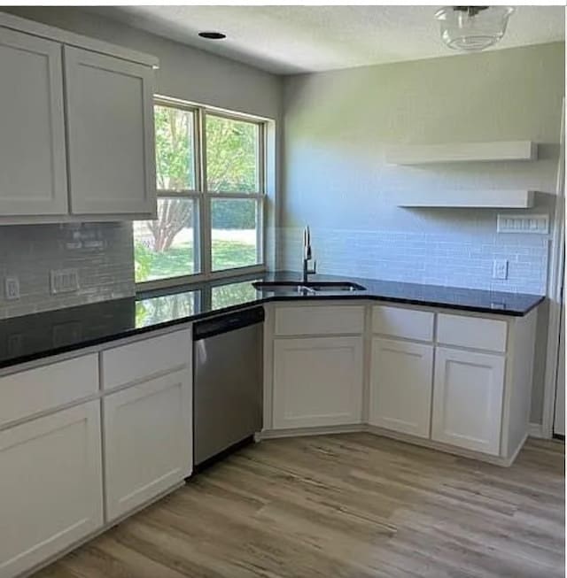 kitchen featuring open shelves, stainless steel dishwasher, a sink, and backsplash