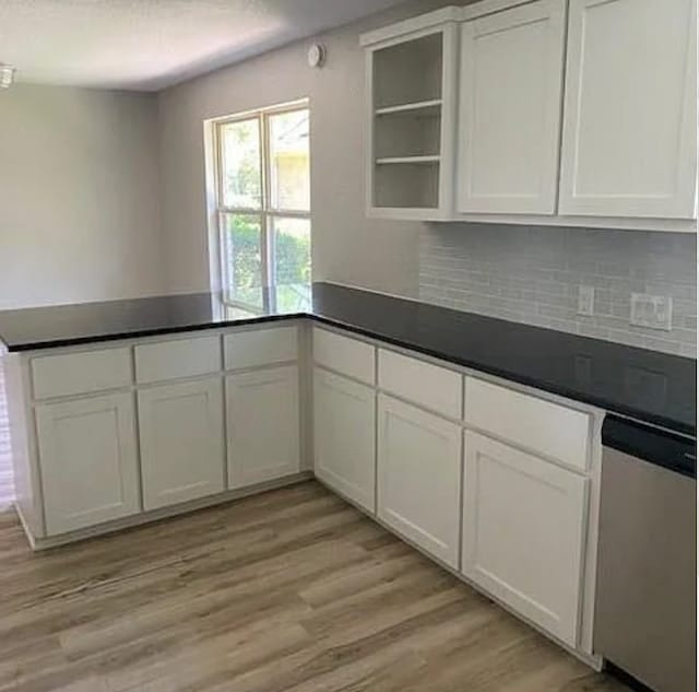kitchen featuring backsplash, dark countertops, open shelves, a peninsula, and white cabinetry