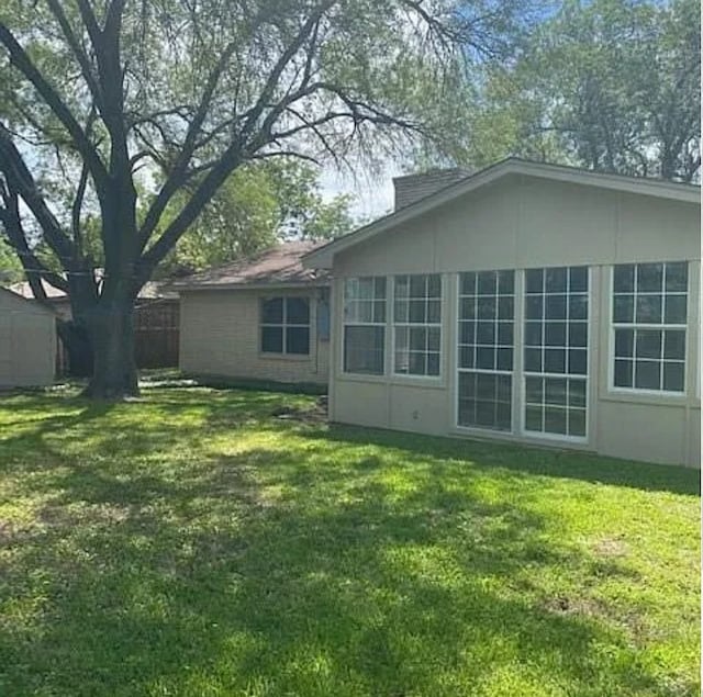 rear view of property featuring a lawn and fence