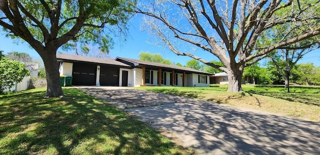 ranch-style house featuring an attached garage, driveway, and a front yard