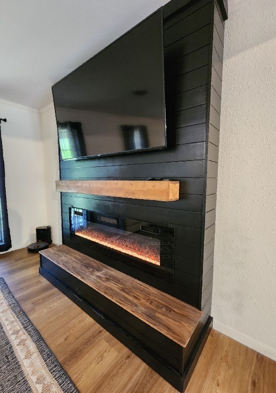 room details with a glass covered fireplace, wood finished floors, crown molding, and baseboards