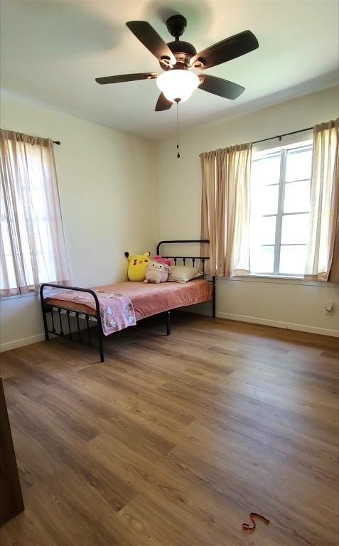 bedroom with wood finished floors, baseboards, and ceiling fan