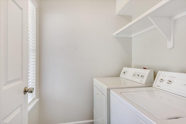 clothes washing area with washing machine and clothes dryer, a healthy amount of sunlight, laundry area, and baseboards