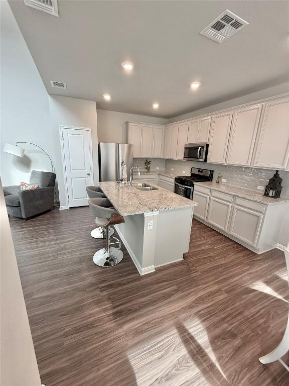 793 Lone Peak Way, Dripping Springs, TX 78620 - kitchen with appliances with stainless steel finishes, dark wood finished floors, a kitchen island with sink, white cabinets, and recessed lighting