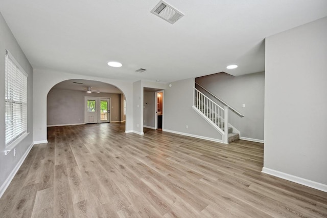 8139 Evadean Cir, Austin, TX 78745 - unfurnished living room featuring light wood-style floors, baseboards, stairs, and arched walkways