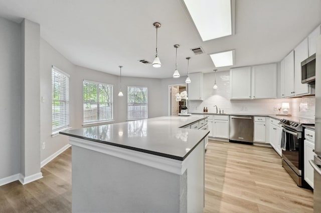 8139 Evadean Cir, Austin, TX 78745 - kitchen with stainless steel appliances, a sink, backsplash, white cabinetry, and light wood-style floors