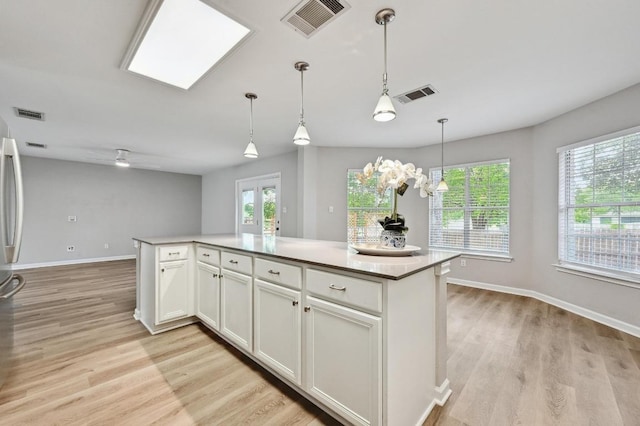 8139 Evadean Cir, Austin, TX 78745 - kitchen featuring light wood-style flooring, white cabinetry, a kitchen island, and baseboards