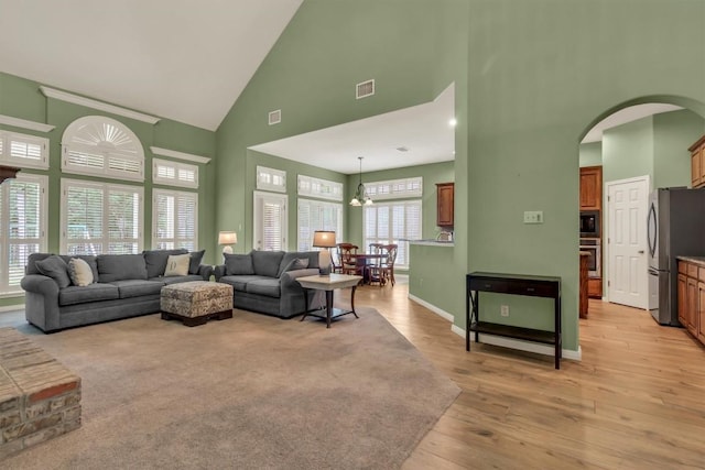 3820 Lagoona Dr, Round Rock, TX 78681 - living area with high vaulted ceiling, arched walkways, light wood-style floors, and baseboards