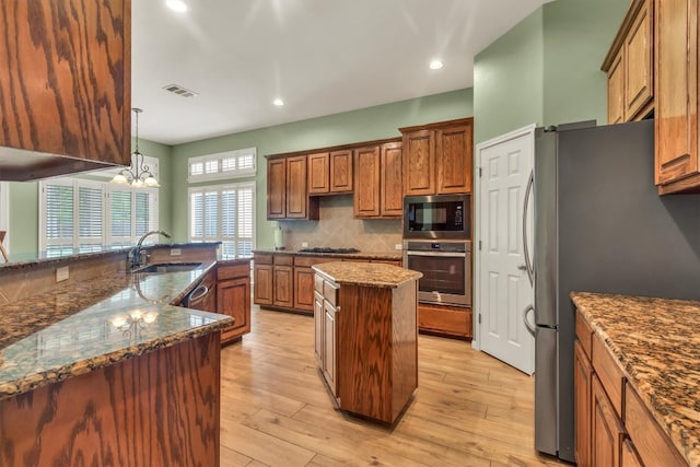 3820 Lagoona Dr, Round Rock, TX 78681 - kitchen with stainless steel appliances, a sink, a kitchen island, brown cabinets, and tasteful backsplash