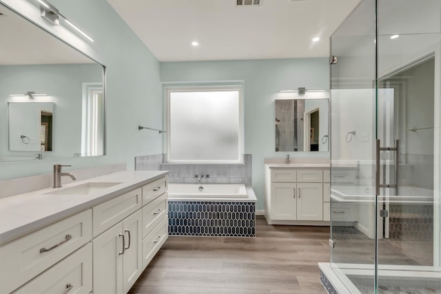 3820 Lagoona Dr, Round Rock, TX 78681 - bathroom with two vanities, a garden tub, a stall shower, wood finished floors, and recessed lighting