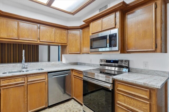 502 Grace Ln, Austin, TX 78746 - kitchen with appliances with stainless steel finishes, a sink, brown cabinets, and light stone countertops