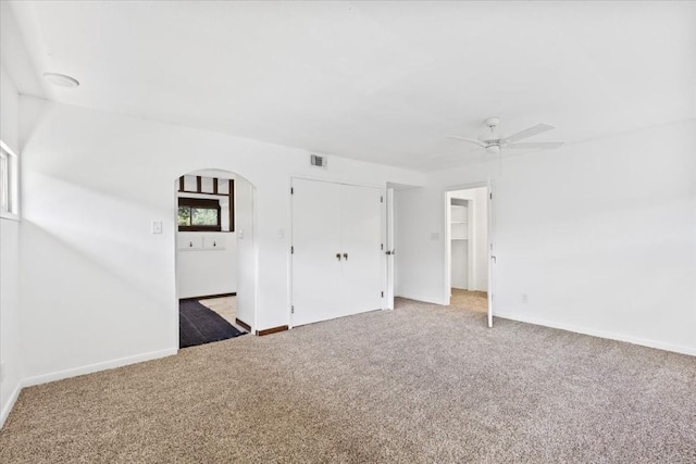502 Grace Ln, Austin, TX 78746 - unfurnished bedroom with arched walkways, light carpet, baseboards, and a ceiling fan