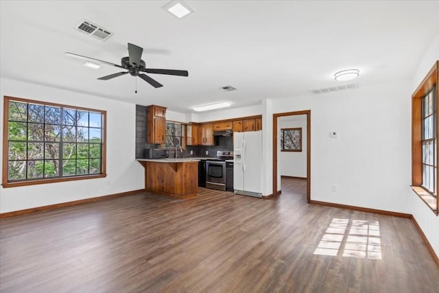 502 Grace Ln, Austin, TX 78746 - kitchen featuring white fridge with ice dispenser, electric range, brown cabinetry, baseboards, and under cabinet range hood