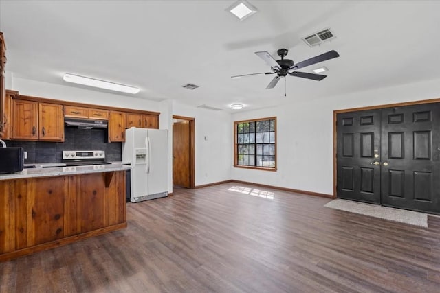 502 Grace Ln, Austin, TX 78746 - kitchen featuring white refrigerator with ice dispenser, stainless steel range with electric stovetop, under cabinet range hood, brown cabinets, and dark wood finished floors