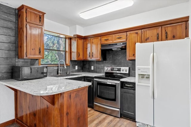502 Grace Ln, Austin, TX 78746 - kitchen featuring white fridge with ice dispenser, stainless steel electric range oven, a sink, under cabinet range hood, and a peninsula