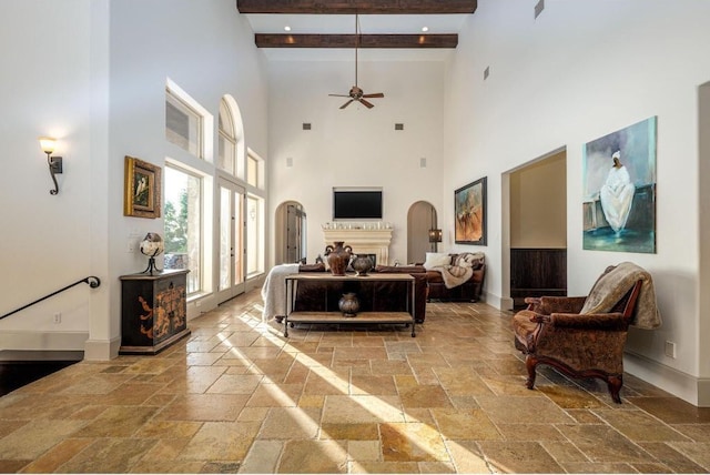 8315 Lime Creek Rd, Volente, TX 78641 - living room with stone tile floors, baseboards, a high ceiling, a ceiling fan, and beamed ceiling
