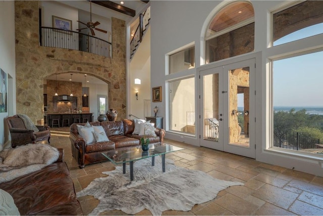 8315 Lime Creek Rd, Volente, TX 78641 - living area featuring stone tile flooring, a high ceiling, french doors, arched walkways, and a ceiling fan
