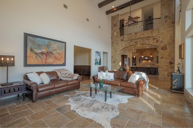 8315 Lime Creek Rd, Volente, TX 78641 - living room with stone tile floors, a high ceiling, a ceiling fan, arched walkways, and beam ceiling
