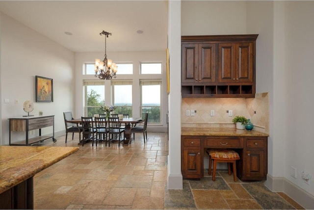8315 Lime Creek Rd, Volente, TX 78641 - kitchen featuring stone tile flooring, backsplash, a chandelier, baseboards, and pendant lighting