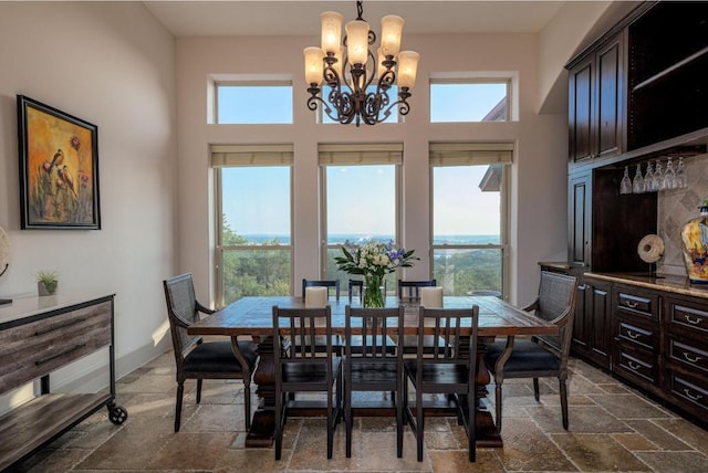 8315 Lime Creek Rd, Volente, TX 78641 - dining area with a chandelier, stone tile flooring, healthy amount of natural light, and a towering ceiling