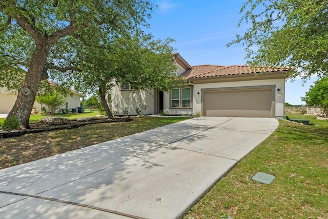 mediterranean / spanish house featuring a tiled roof, stucco siding, driveway, a front yard, and a garage