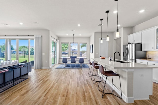 2609 Antalya Loop, Leander, TX 78641 - kitchen featuring stainless steel fridge with ice dispenser, light wood-style floors, recessed lighting, white cabinets, and light countertops