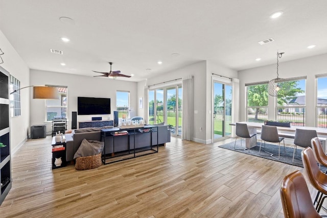 living area with baseboards, visible vents, light wood-type flooring, and recessed lighting