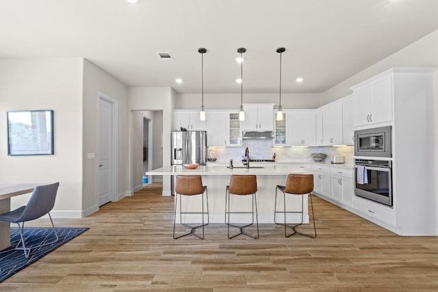 kitchen featuring under cabinet range hood, appliances with stainless steel finishes, visible vents, and light wood-style flooring