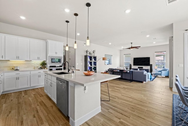 kitchen featuring light wood-style floors, stainless steel appliances, white cabinetry, and a sink
