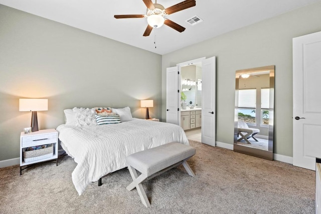 bedroom with ensuite bath, baseboards, visible vents, and light colored carpet