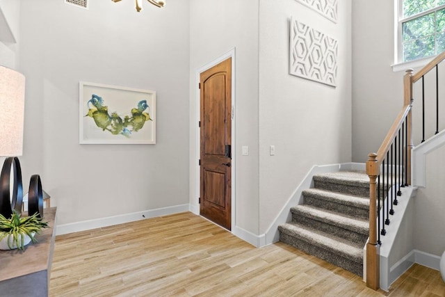 entrance foyer with visible vents, baseboards, wood finished floors, and stairs