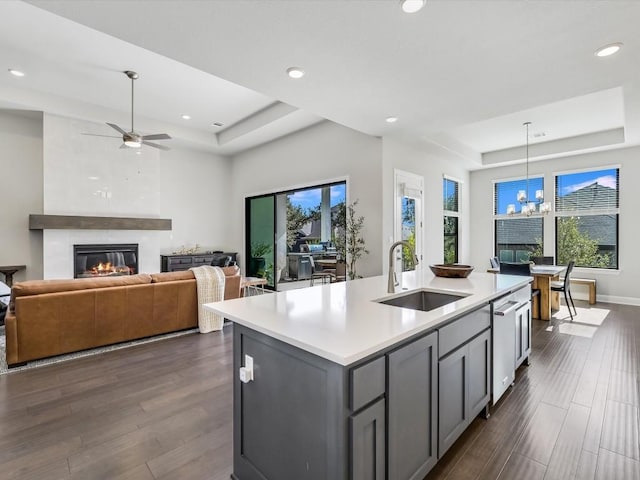 kitchen with a sink, recessed lighting, ceiling fan with notable chandelier, light countertops, and a raised ceiling