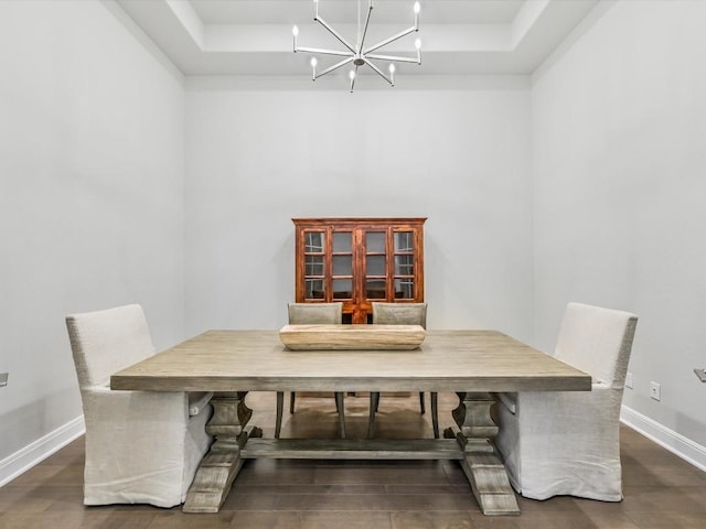 dining room with a tray ceiling, baseboards, dark wood-type flooring, and an inviting chandelier