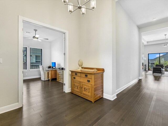 hallway with dark wood finished floors, baseboards, a chandelier, and visible vents
