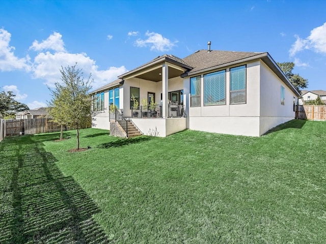 back of property with stairway, a fenced backyard, a yard, and stucco siding