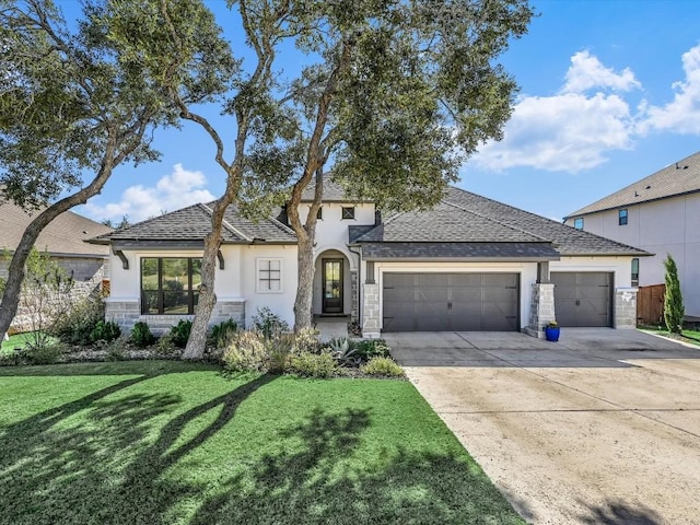 view of front of property with stucco siding, an attached garage, driveway, stone siding, and a front yard